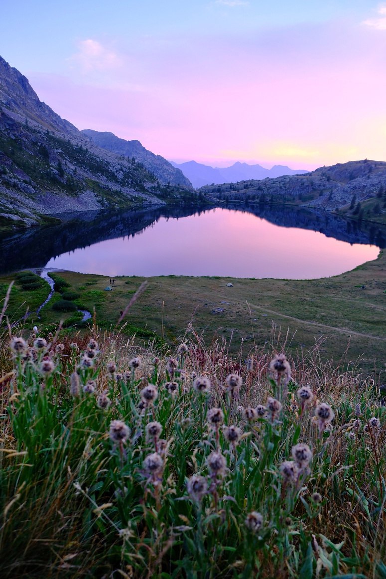 Un lac au creux des montagnes, sous un ciel rose