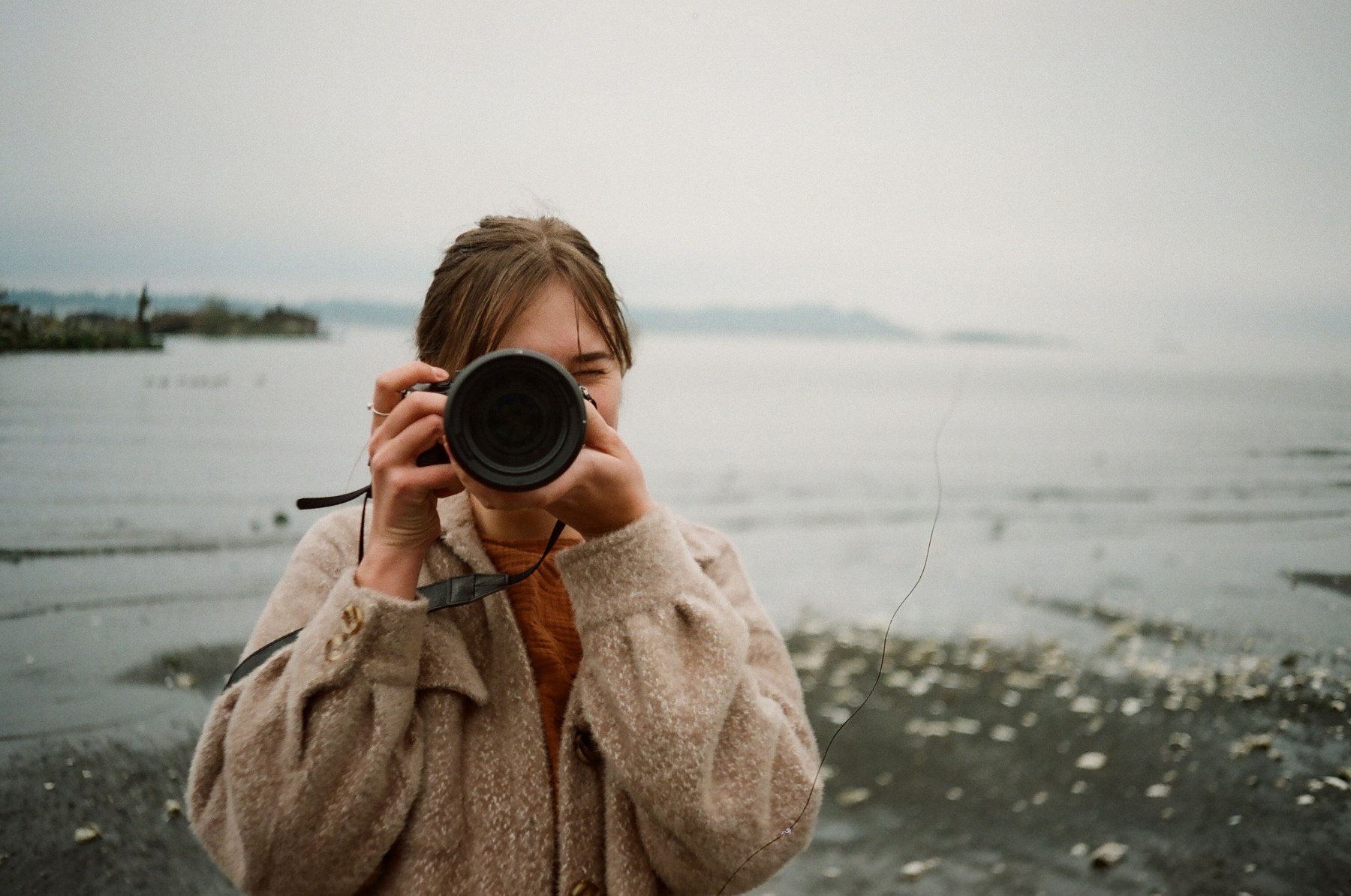 Une photographe derrière son appareil, au bord de l’eau